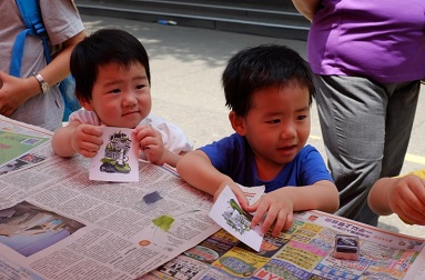 Children making colorful bookplate rubbings at a booth set up by the NTHU library. 