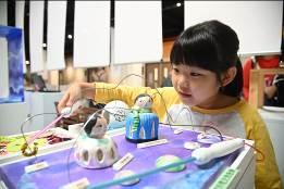 
Young visitor playing with a piece of interactive art titled Happiness Is a Two-way Circuit.