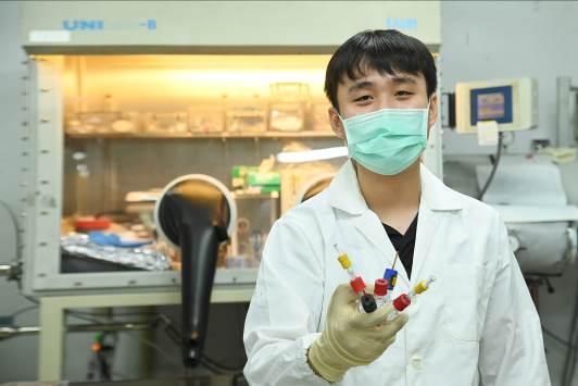 
Lu in his lab holding the apparatus he designed for measuring electrochemical reactions.