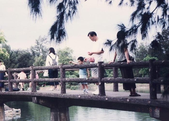 Old photo of Tsai Jinbu (蔡進步) and his children feeding fish from the Kegong Bridge.
