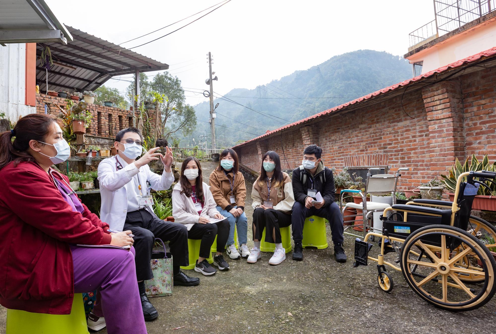 Family physician Chiou Jin-der (邱金德) (second from left) answering questions from NTHU students at a patient’s home in Wufeng.
