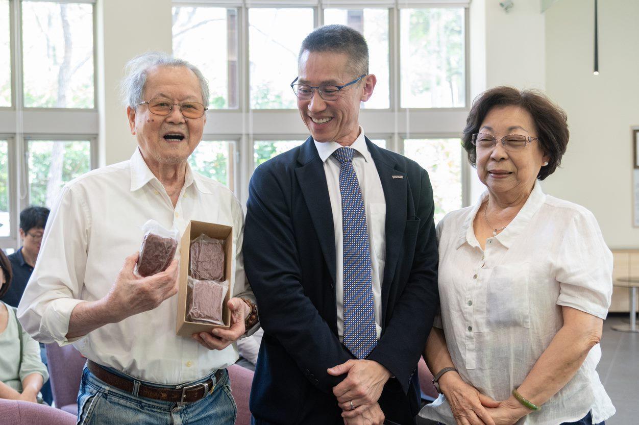 NTHU President W. John Kao (高為元) (center) presents Chun-ming Huang (黃春明) with a gift of purple potato rice noodles.