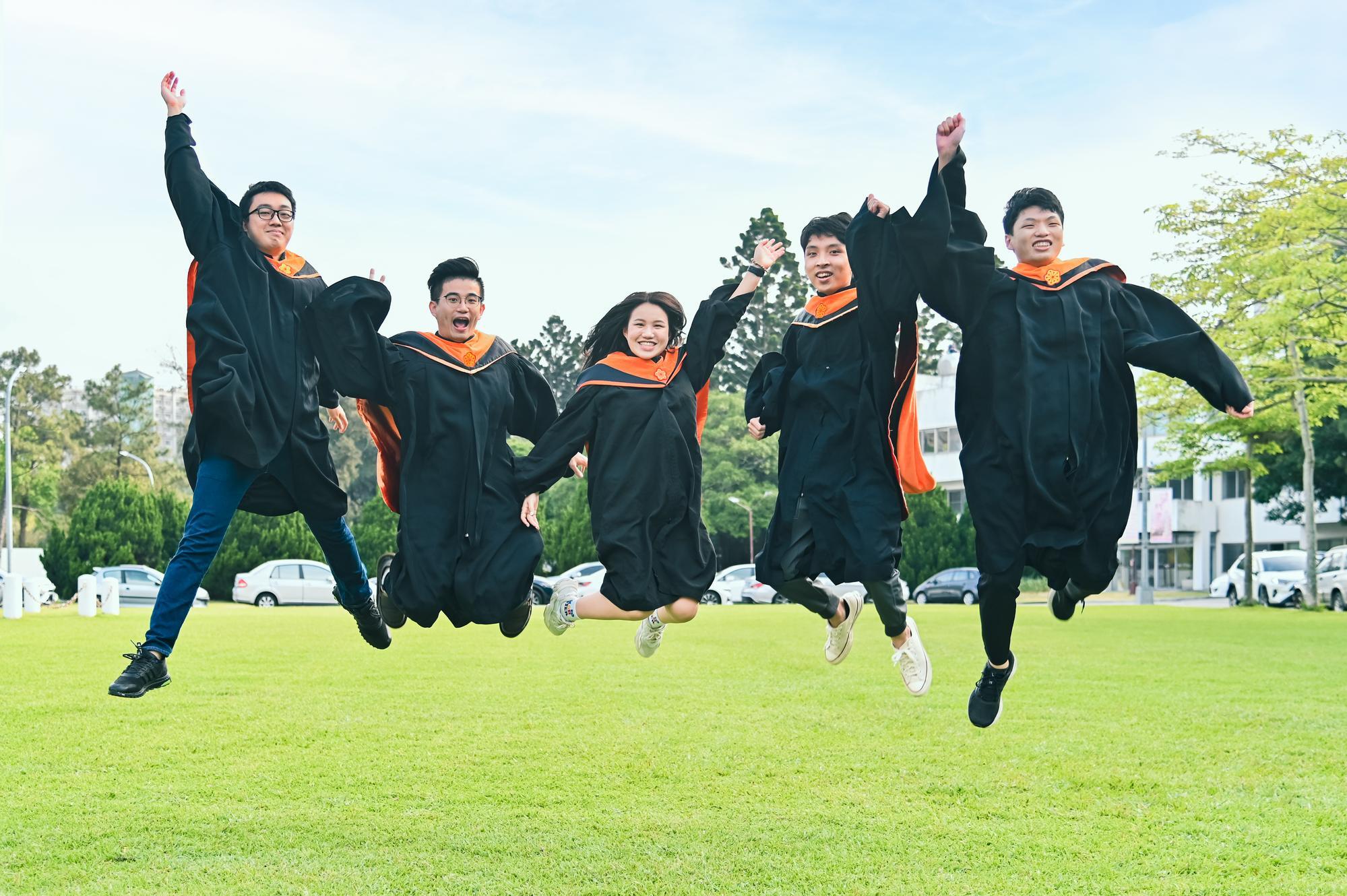 NTHU graduates joyfully leaping on the lawn.