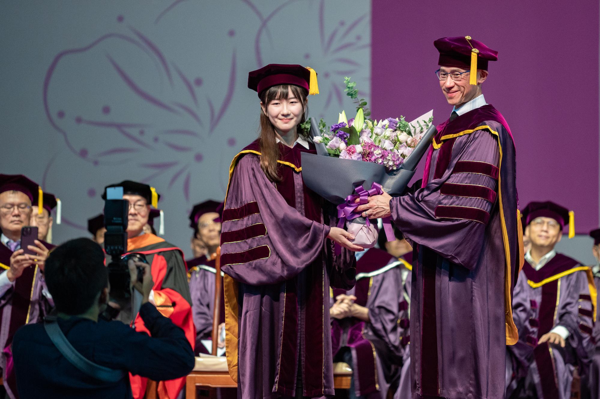 Chi-hsien Wang (王祺嫻) (left), a Ph.D. student from the Department of Chemical Engineering, presents a bouquet of flowers to President W. John Kao (高為元) on behalf of the graduating students.