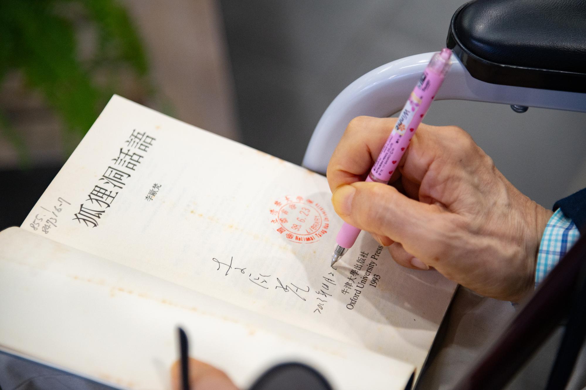 Dr. Leo Ou-fan Lee (李歐梵) signing the title page of his work, Discourses from the Fox Burrow, which is part of the collection at NTHU's library.