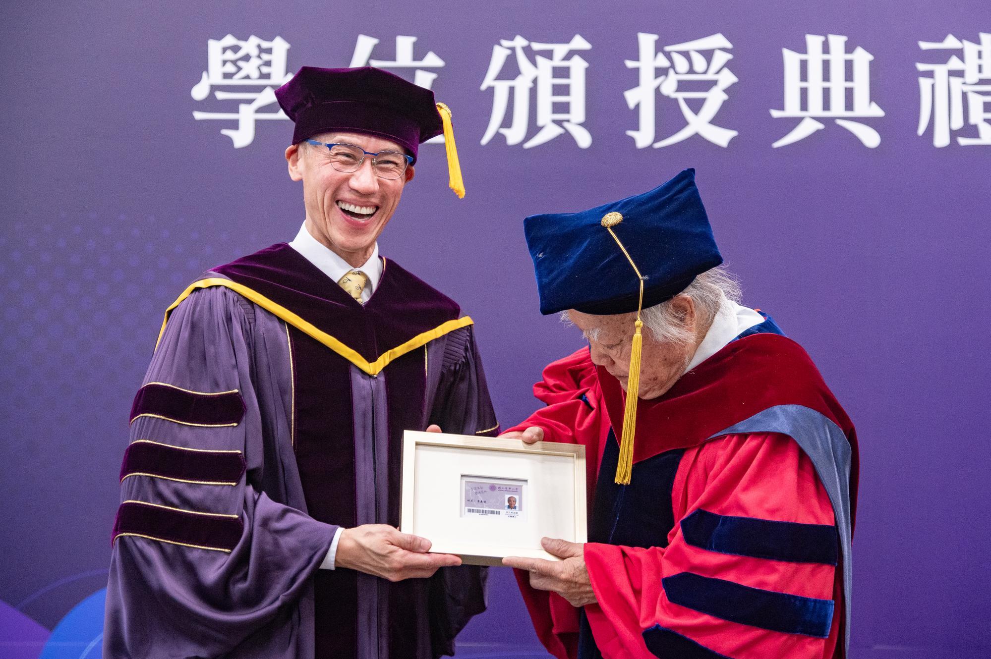 Dr. Yi-Fa Lee (李義發) (right) carefully examines the framed Permanent Alumni Card, realizing the benefits of borrowing books from the NTHU library and enjoying parking privileges.