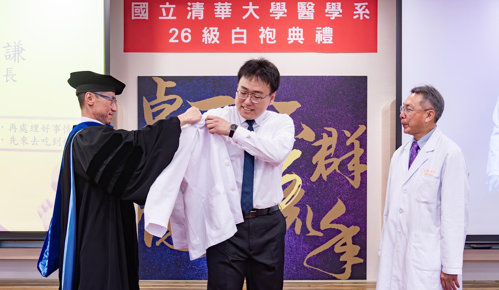 President W. John Kao (高為元) (left) adorned Ho-Chien Shen (沈和謙), a member of the first class of medical students at NTHU, with a white coat.