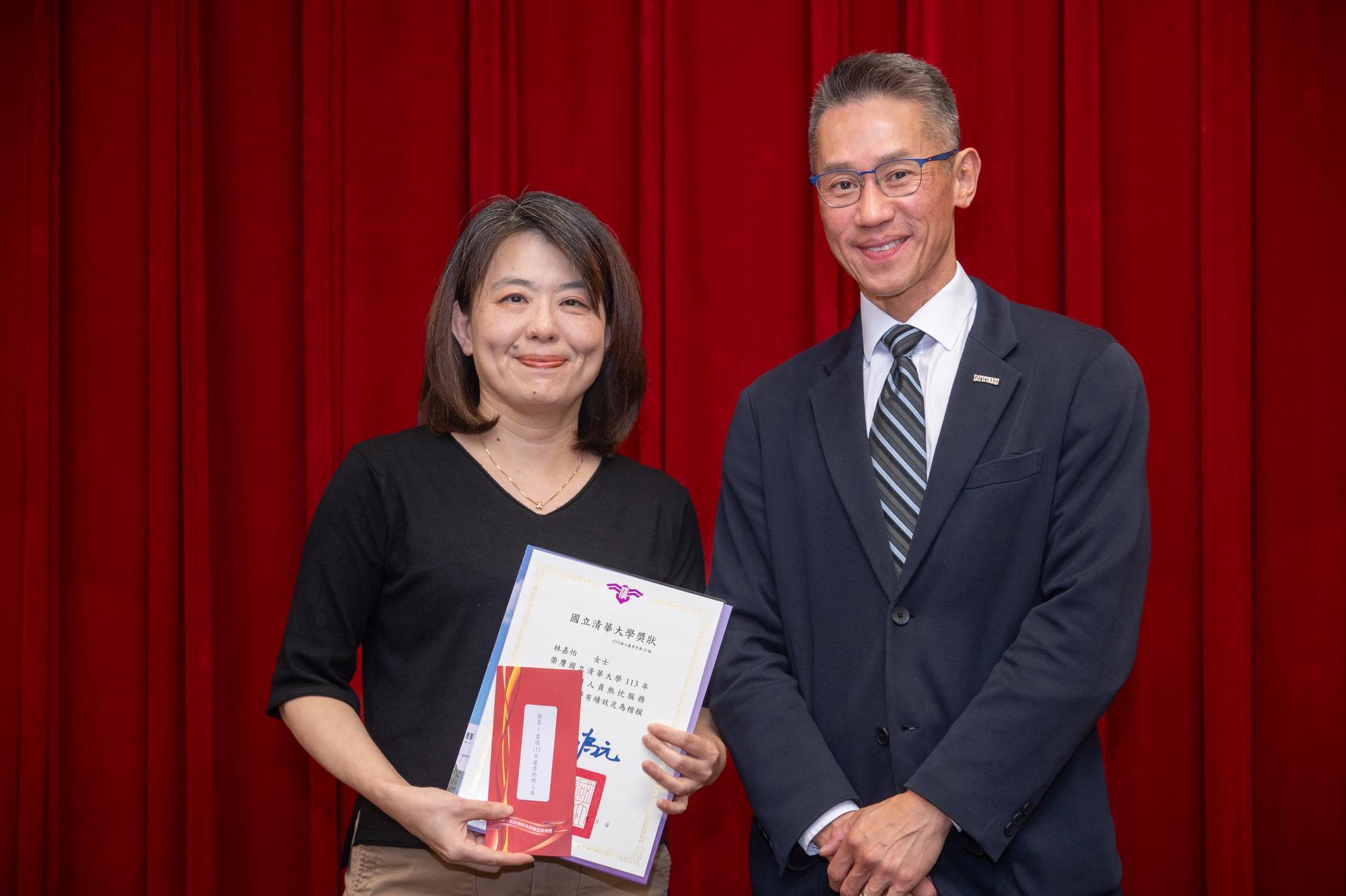 NTHU President W. John Kao (right) presents an award and bonus to Chia-Yi Lin (林嘉怡), Deputy Manager of the Division of General Academic Affairs in the Office of Academic Affairs.