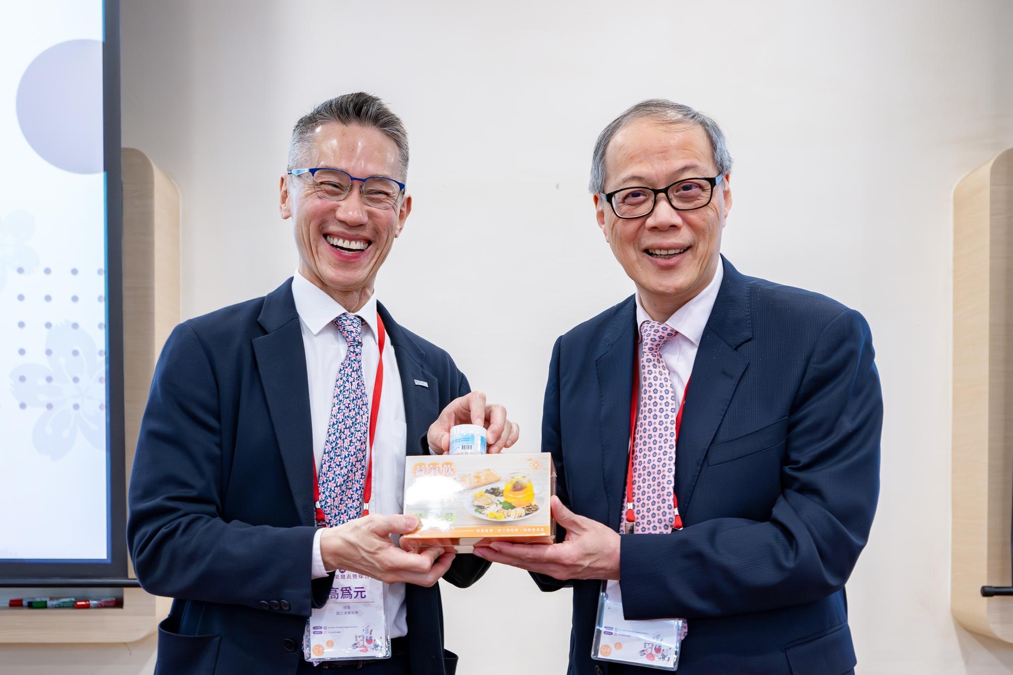 Chen (right) presenting NTHU president W. John Kao with a health drink developed at Chang Gung.