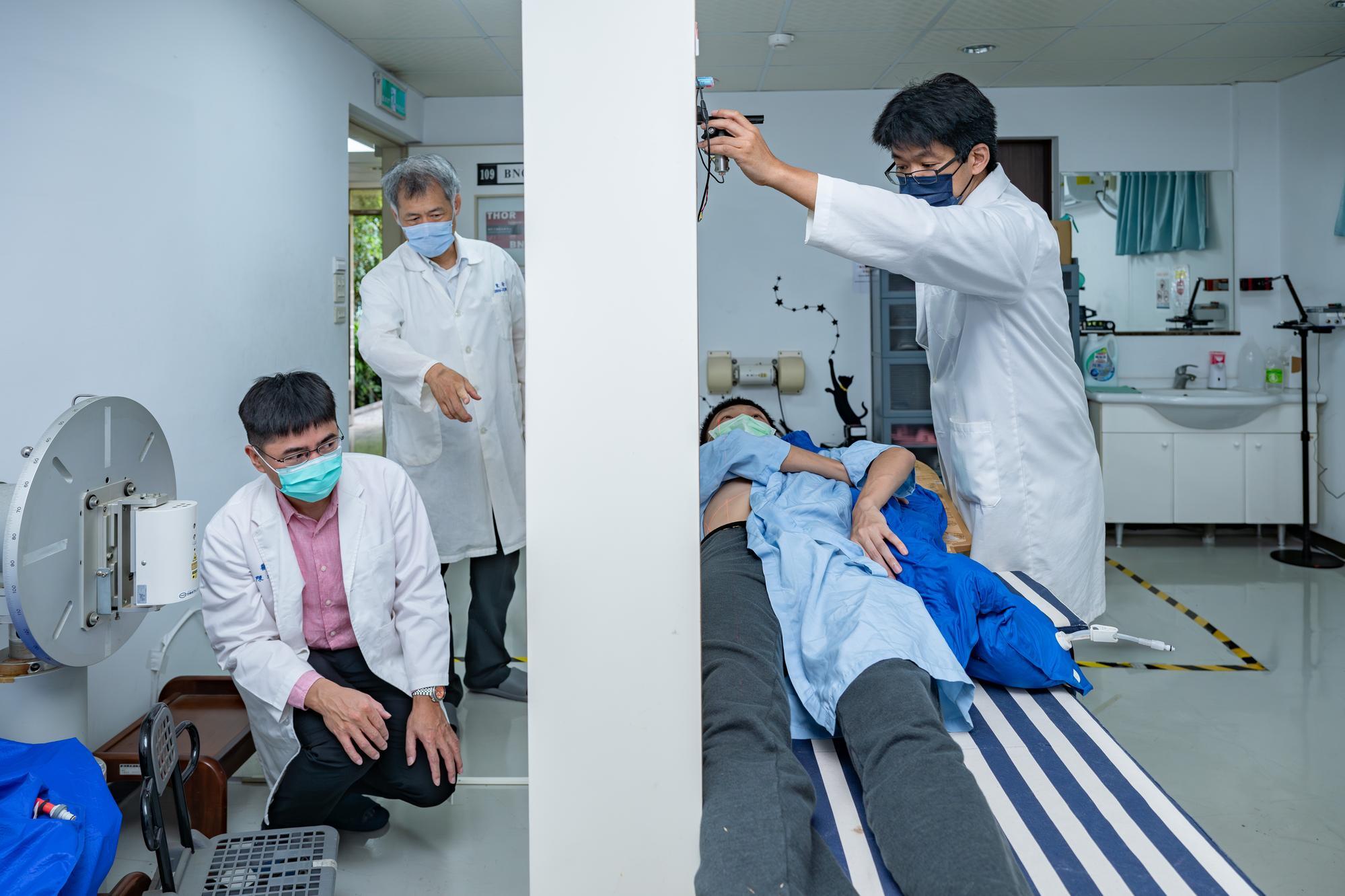 Chen (left) with Jinn-Jer Peir（裴晉哲） and Yung-Shin Tseng（曾永信） of the NSTDC at NTHU showing the procedure in which the neutron beam enters the patient's body.  