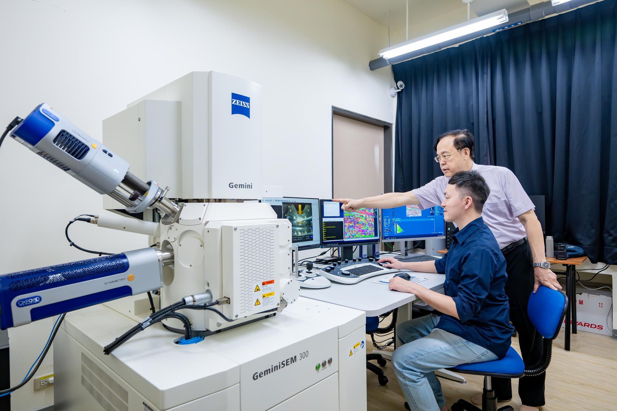 Jien-Wei Yeh (葉均蔚) (rear) showing Wei-Lin Hsu (許瑋麟) how to use a scanning electron microscope to observe the lattice structure of a high-entropy alloy.