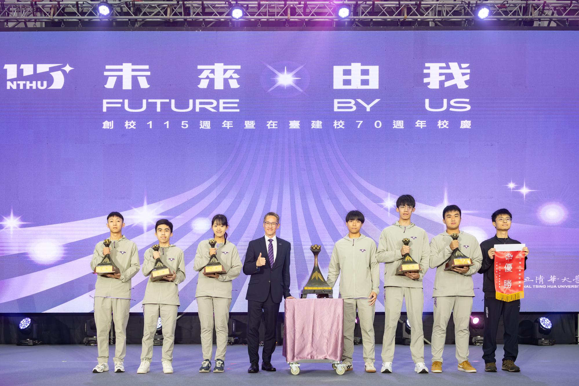 The university's championship-winning athletic teams from the Mei-Chu Games present their trophies at the anniversary assembly, with President W. John Kao receiving the overall championship trophy on behalf of NTHU