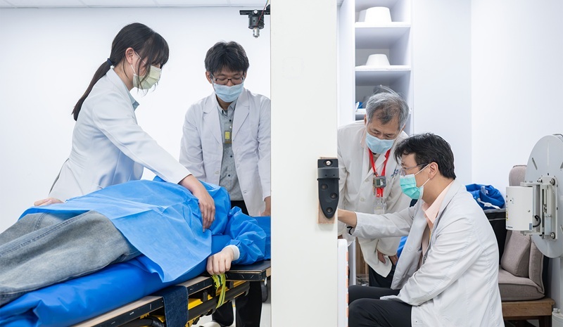 NTHU nuclear engineers Jinn-Jer Peir (second from right) and Yung-Shin Tseng (second from left), along with TVGH physician Yi-Wei Chen (right), simulate the positioning of the neutron beam irradiation field for a breast cancer patient.